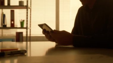 Yan görüşlü, karanlık siluet bir adam dijital tablet kullanarak bir video görüşmesinde konuşuyor. Bir erkek yönetici, tasarımcı ya da programcı akşamları karanlık bir ofiste masada otururken çalışır. Kapat.