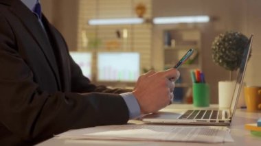 Genç bir adamın yan görüntüsü cep telefonuyla mesajlaşıyor. Patron, yönetici, programcı ya da iş adamı ofisteki bir masada oturuyor. Ofis işi, serbest çalışma, eğitim, iş konsepti