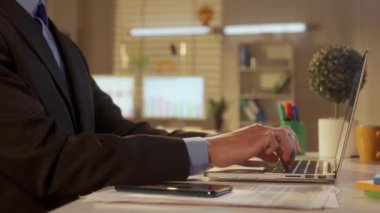 Genç bir adamın yan görüntüsü dizüstü bilgisayarda klavyeye yazı yazması ve cep telefonuyla mesajlaşmasıdır. Patron, yönetici, programcı ya da iş adamı ofisteki bir masada oturuyor. Ofis işi
