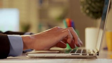 Bilgisayarla çalışan takım elbiseli genç bir adamın yan görüntüsü. Baş, yönetici, programcı veya iş adamı dizüstü bilgisayarda klavye kullanıyor. Ofis işi, serbest çalışma, eğitim, iş konsepti