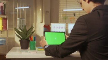 Genç bir adamın yeşil ekran dijital tableti var. Yönetici, programcı ya da iş adamı ofisteki bir masada oturuyor. Metnin veya resmin için şablon yeri