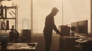 Genç bir adamın silueti eşyalarını bir kutuya koyar. Bir erkek yönetici, gece vakti karanlık bir ofiste arka ışıklandırma penceresinin yanında işten atıldıktan sonra eşyaları alır. Ofiste çalışma konsepti
