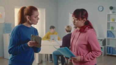 Genç Avrupalı ve Asyalı kadınlar yeni bir iş projesini tartışıyor ve dijital tablet ve bir belgede verileri karşılaştırıyorlar. Modern bir ofiste birlikte çalışan bir grup genç yönetici. İşbirliği yap.