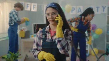 Asyalı temizlikçi kadın cep telefonuyla konuşuyor ve mutlu bir şekilde gülümsüyor. Afrikalı bir Amerikalı kadın süpürürken Avrupalı bir adam çöp torbasına çöp koyar. Mavi tulumlu, çok uluslu bir temizlik ekibi.