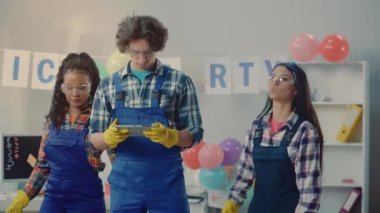 Mavi tulumlu çok uluslu bir temizlikçi grubu bir odayı teftiş ediyor ve dijital tablet kullanarak partiden sonra ofis temizliği yapmayı planlıyor. Temizlik hizmeti konsepti. Bir sürü çöp var.