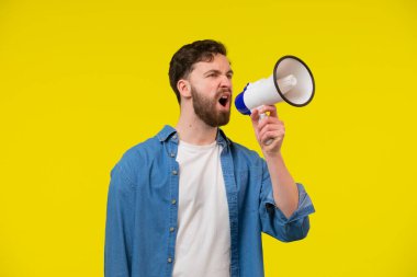 Izole sarı duvar üzerinde yakışıklı adam bir megafon ile bağırıyor