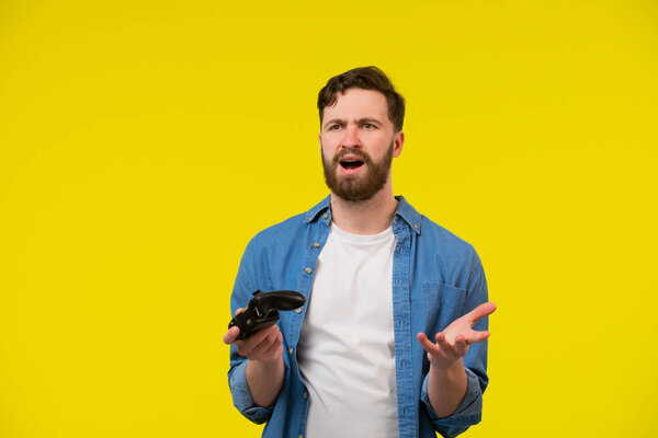 Close up photo of nervous scary fan of video games, he is holding a console, isolated on bright yellow background, copyspace