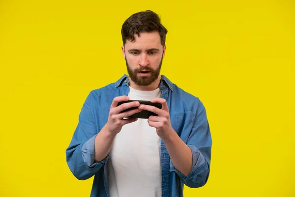 Portrait Excited Young Man Playing Games Mobile Phone Isolated Yellow — Stock Photo, Image