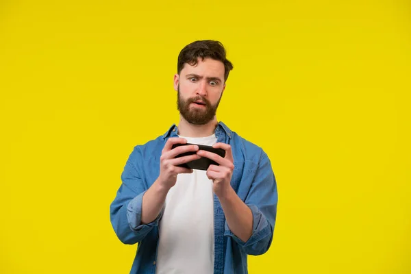 Porträtt Upphetsad Ung Man Spelar Spel Mobiltelefon Isolerad Över Gul — Stockfoto