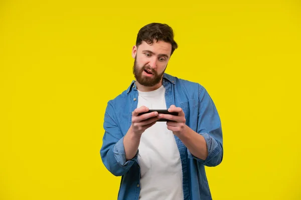Portrait Excited Young Man Playing Games Mobile Phone Isolated Yellow — Stock Photo, Image