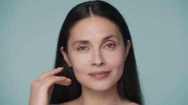 Genç bir kadın manikürlü elleriyle çenesini kapatıyor ve yüzünü sağa sola çeviriyor. Kadın doğru yüz hatlarını yakından gösteriyor. Doğal güzellik, yüz bakımı, kozmetoloji, plastik