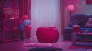 Bastırılmış ışıkları olan bir parti için dekore edilmiş bir oda ve dönen bir disko topundan yansıyan renkli röfleler. Masanın üzerinde kağıt bardaklar, pizza ve patlamış mısır var. Her şey hazır.