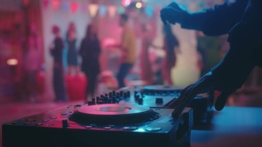 Erkek eller DJ konsolunda dans eden insanların bulanık arka planlarıyla müziği karıştırıyor. Tatil, kutlama, disko konsepti.