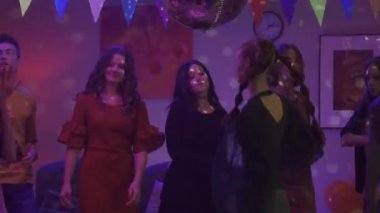 Bir grup arkadaş bir partide gayretle dans ediyor. Siyahlı kız, gayri resmiyet, tevazu ve utangaçlığıyla herkes arasında göze çarpıyor. Kapatın. Parti, doğum günü, kutlama. HDR BT2020 HLG