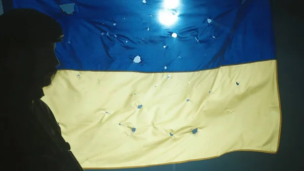 銃弾の穴で覆われたウクライナの旗の背景にライフルで兵士のシルエットの側面図 閉めろ ウクライナの防衛に立っている兵士 概念として — ストック写真