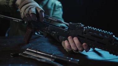 Kalaşnikof saldırı tüfeğinin tüm detaylarını ahşap bir masada toplayın. Erkekler Kalaşnikof saldırı tüfeğinin detaylarını toplar, tetiği kontrol eder ve fünyeyi takar. Ordu