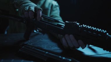 Kalaşnikof saldırı tüfeğinin tüm detaylarını ahşap bir masada toplayın. Erkekler Kalaşnikof saldırı tüfeğinin detaylarını toplar, tetiği kontrol eder ve fünyeyi takar. Ordu