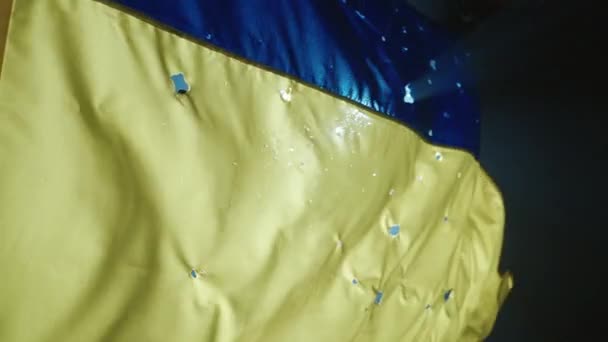 乌克兰人的蓝色黄色旗帜在黑色背景上被聚光灯照亮 乌克兰国旗上布满了弹孔 与乌克兰站在一起 慢动作 — 图库视频影像