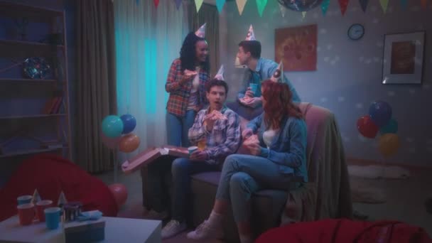 Grupa Młodych Ludzi Imprezowych Kapeluszach Pizzę Pije Drinki Siedząc Kanapie — Wideo stockowe