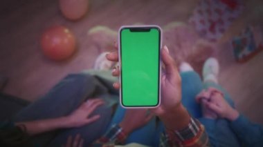 Kucağında yeşil ekran telefon tutan Afrikalı Amerikalı kadınların elleri. Partideki bir kız telefonda arkadaşlarına bir şey gösterir ve onlar da onaylar, güzel. Video izlemek, fotoğraf çekmek.