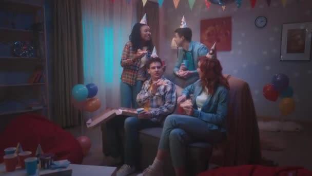 Grupa Młodych Ludzi Imprezowych Kapeluszach Pizzę Pije Drinki Siedząc Kanapie — Wideo stockowe