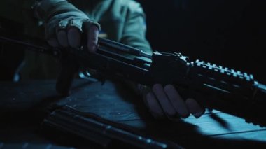 Kalaşnikof saldırı tüfeğinin tüm detaylarını ahşap bir masada toplayın. Erkekler Kalaşnikof saldırı tüfeğinin detaylarını toplar, tetiği kontrol eder ve fünyeyi takar. Ordu