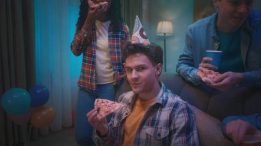 Kafasında şenlik şapkası olan kıvırcık saçlı bir adam elinde bir dilim pizzayla kameraya sinsice bakar. Partideki arkadaşlar sosyalleşir ve ikram ve içkinin tadını çıkarırlar. Evde doğum günü partisi