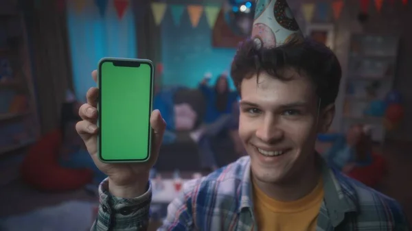 Кудрявый Парень Праздничной Шляпе Улыбаясь Показывает Телефон Зеленым Экраном Крупный — стоковое фото