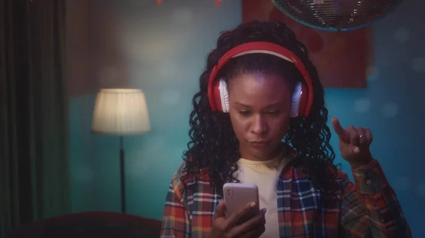 Afroamerikansk Tjej Röda Trådlösa Hörlurar Bläddrar Igenom Spellista Telefonen Med — Stockfoto