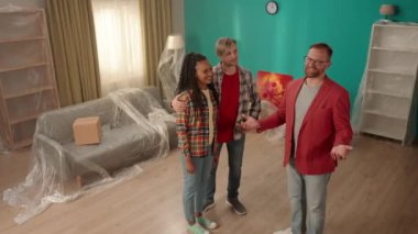 Emlakçı bir kaç gencin dairesini gösteriyor. Afrikalı Amerikalı bir kız bir emlakçıyla el sıkışıyor, anlaşmayı kutluyor, yüksek kaliteli profesyonel hizmet için teşekkürler. Görünüm