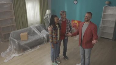 Emlakçı bir kaç gencin dairesini gösteriyor. Afrikalı Amerikalı bir kadın emlakçıyla el sıkışıyor, anlaşmayı kutluyor, yüksek kaliteli profesyonel hizmet için teşekkürler. Görünüm