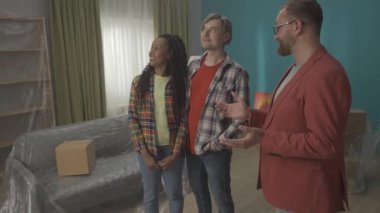Emlakçısı olan genç bir çift satın almak ya da kiralamak için bir daireyi ziyaret ediyor. Apartman dairesi. Modern bir odada mutlu bir çift. Emlak müşterisi. Ağır çekim. HDR BT2020 HLG Malzemesi