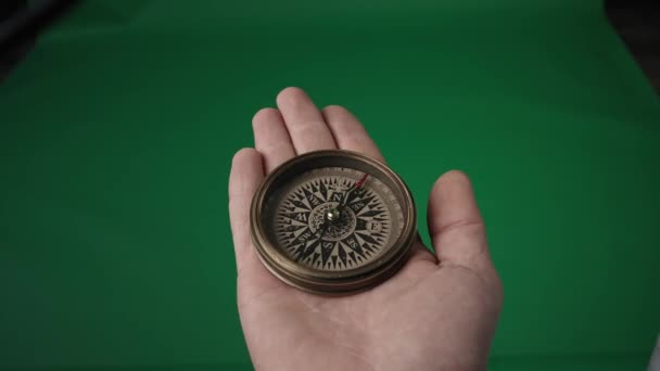 旅行のコンセプト 緑の画面上の開いている男性の手のひらに回転矢印と磁気コンパス — ストック動画