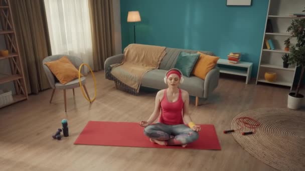 Рыжая Молодая Женщина Наушниках Сидит Позе Лотоса Медитирует Практикует Йогу — стоковое видео