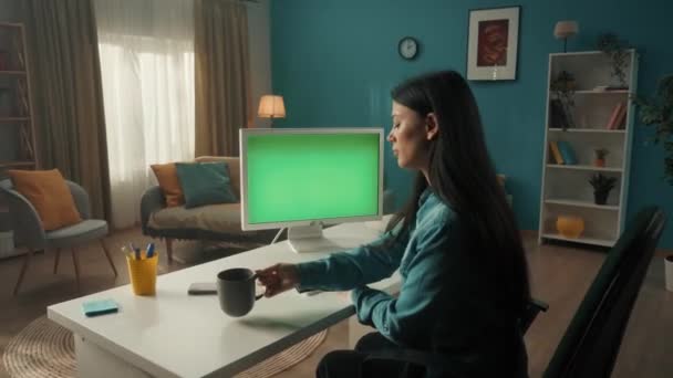 一位年轻妇女正在喝早茶 在一台有绿色屏风的电脑上工作 绿色屏幕计算机监视器关闭 连接的概念 — 图库视频影像
