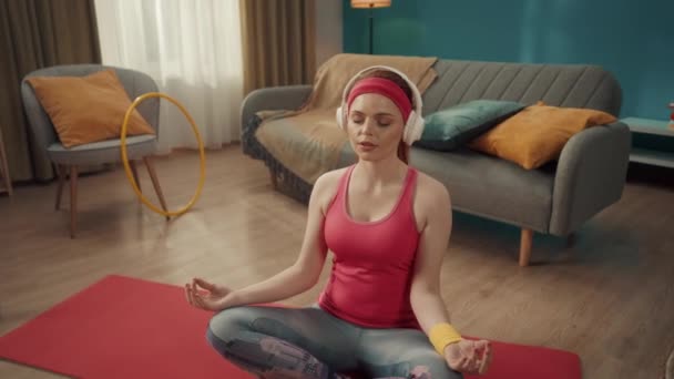 Eine Rothaarige Junge Frau Mit Kopfhörern Sitzt Einer Lotusposition Meditiert — Stockvideo