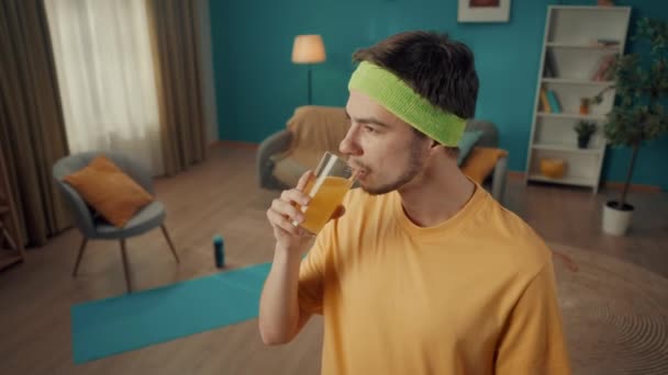 一个带着头巾的年轻人在家锻炼后的肖像 一个男人喜欢喝新鲜的挤榨果汁 新鲜的背景下的客厅有适合家庭的属性 家庭健康 — 图库视频影像