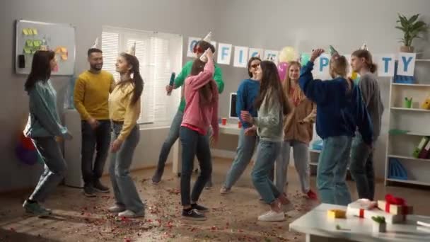 一群戴着节日礼帽和眼镜的同事正在跳舞 玩得很开心 庆祝一个共同的成功 一个生日 一个年轻人用意大利面炸开了一个饼干 公司在办公室 慢动作 — 图库视频影像