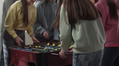 Ofiste iki genç kız takımı masa futbolu oynuyor. Katılımcılardan biri topu masaya attı ve oyun başladı. Ofis çalışanları birlikte eğleniyor. Kapatın. Ofis partisi