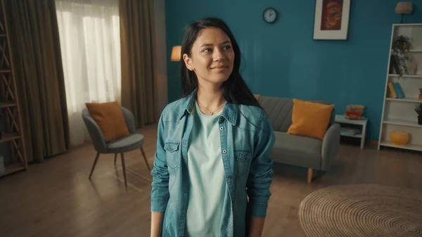 年轻的微笑的亚洲女人在一个干净明亮的客厅里 一个年轻的女人满意地微笑着环视整个房间 — 图库照片