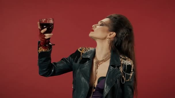 女人把一杯葡萄酒举到脸上 吸入它的香气 厌恶地 不悦地笑着 一个有着红色背景的怪胎女人的画像被污染的饮料概念 — 图库视频影像
