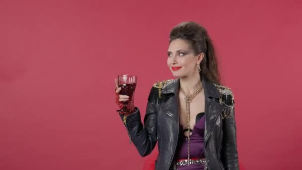 女性はワインのグラスでスタンド ワインの一口を取り それを嘔吐 唇を押すと悲しいことにカメラを覗き込む 赤い背景の女性の肖像画 こぼれた飲み物のコンセプト — ストック動画