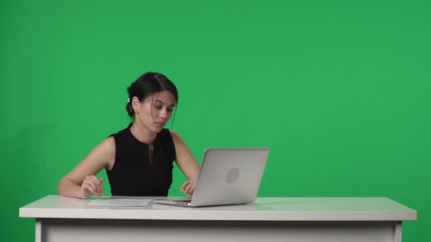 Sunucusu Yeşil Bir Ekranın Arka Planında Stüdyoda Bir Masada Oturuyor — Stok video