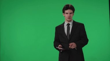 TV Hava Durumu Programı. Stüdyoda, arka planda yeşil bir ekranın karşısında duran spiker. Elinde tabletle bir erkek meteorolog yeşil bir ekrana işaret ediyor. Reklam alanı
