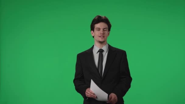 テレビ天気予報番組 アンコールマンは緑のスクリーンを背景にスタジオに立っている 彼の手に論文を持つ男性気象学者は 緑の画面を指します 広告エリア — ストック動画