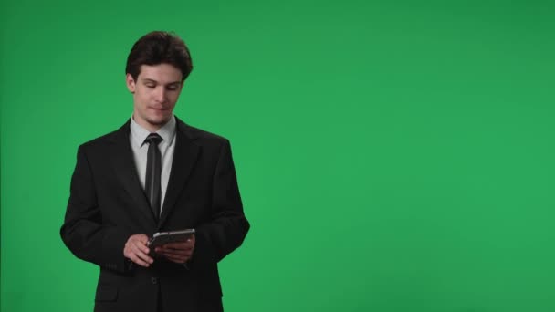 电视直播新闻节目 在一个绿色屏幕的背景下 在演播室报道电视主持人 一个手里拿着平板电脑的男性电视主持人说话 广告区 工作空间模拟 — 图库视频影像