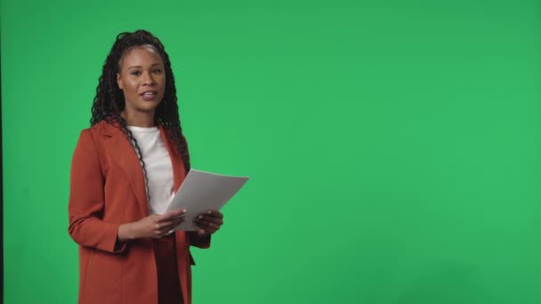 电视直播新闻节目 在一个工作室的绿色屏幕前报道电视节目主持人 手里拿着纸的非裔美国女主播自信地说着话 指着绿色的屏幕 — 图库视频影像