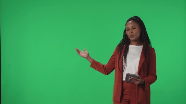 电视天气预报节目 女主播站在工作室里 手里拿着一块石碑 背景是一个绿色的屏幕 非裔美国女气象学家指着绿色屏幕 — 图库视频影像