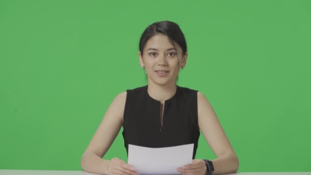아시아 발표자는 탁자에 앉아서 종이에서 정보를 읽는다 스튜디오 프로그램 네트워크 — 비디오