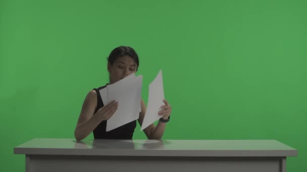 프로그램 어두운 스튜디오에서 화면의 배경에 반하여 발표자는 시작되기 종이를 놓는다 — 비디오